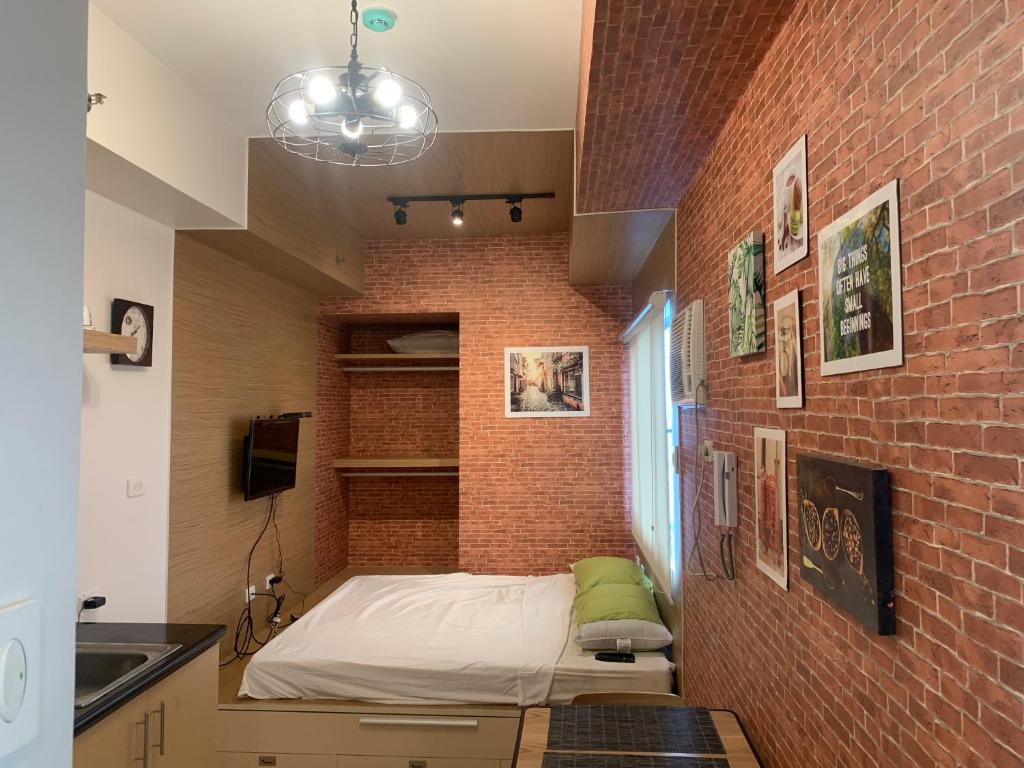 a room with a bed in a brick wall at The grass residences sm north edsa cozy comfortable heart of Quezon City in Manila