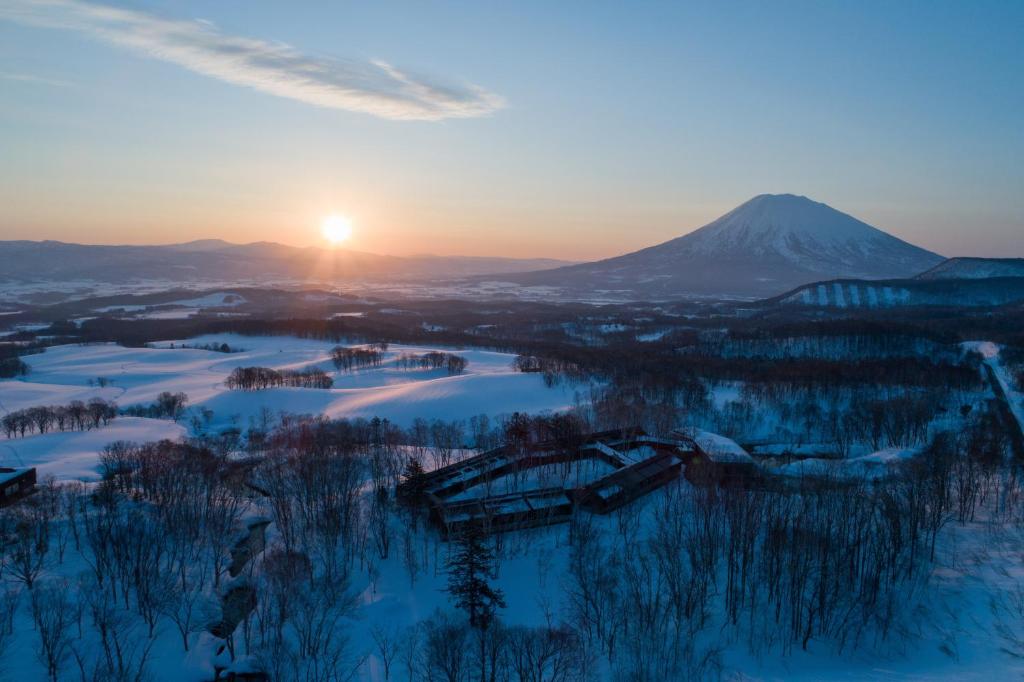 新雪谷的住宿－坐忘林旅館，冬季日落与山背相映