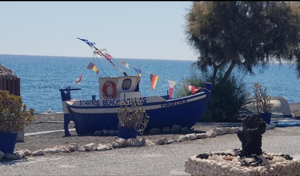 una barca blu seduta sulla spiaggia vicino all'acqua di Stavros Beach Villas a Perivolos