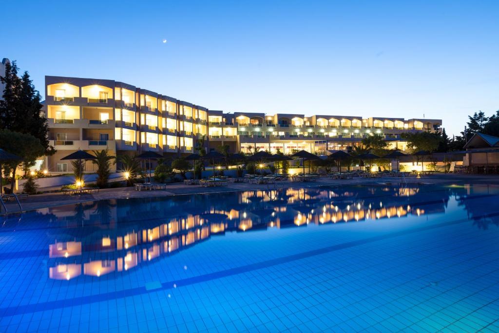 a large pool in front of a building at night at Sovereign Beach Hotel in Kardamaina