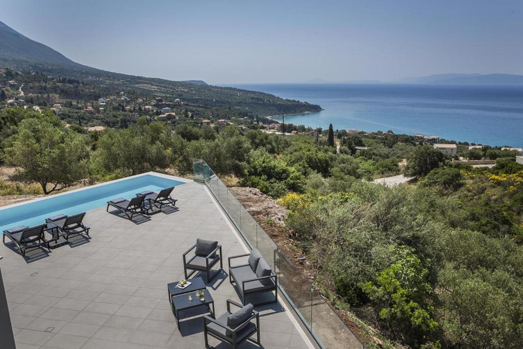 grupa krzeseł siedzących na patio obok basenu w obiekcie Sun N Sea Kefalonia Villa w mieście Kefalonia