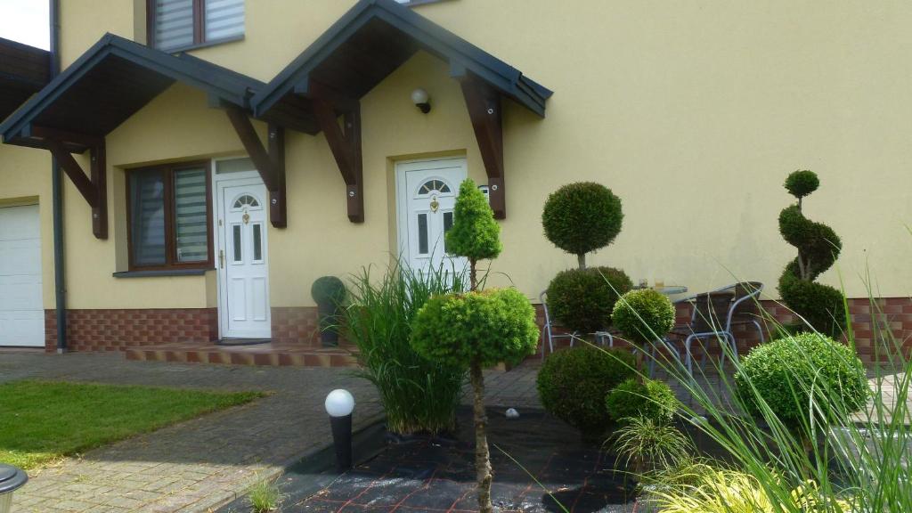 uma casa com uma porta branca e alguns arbustos em Apartament Bieszczady em Myczkowce