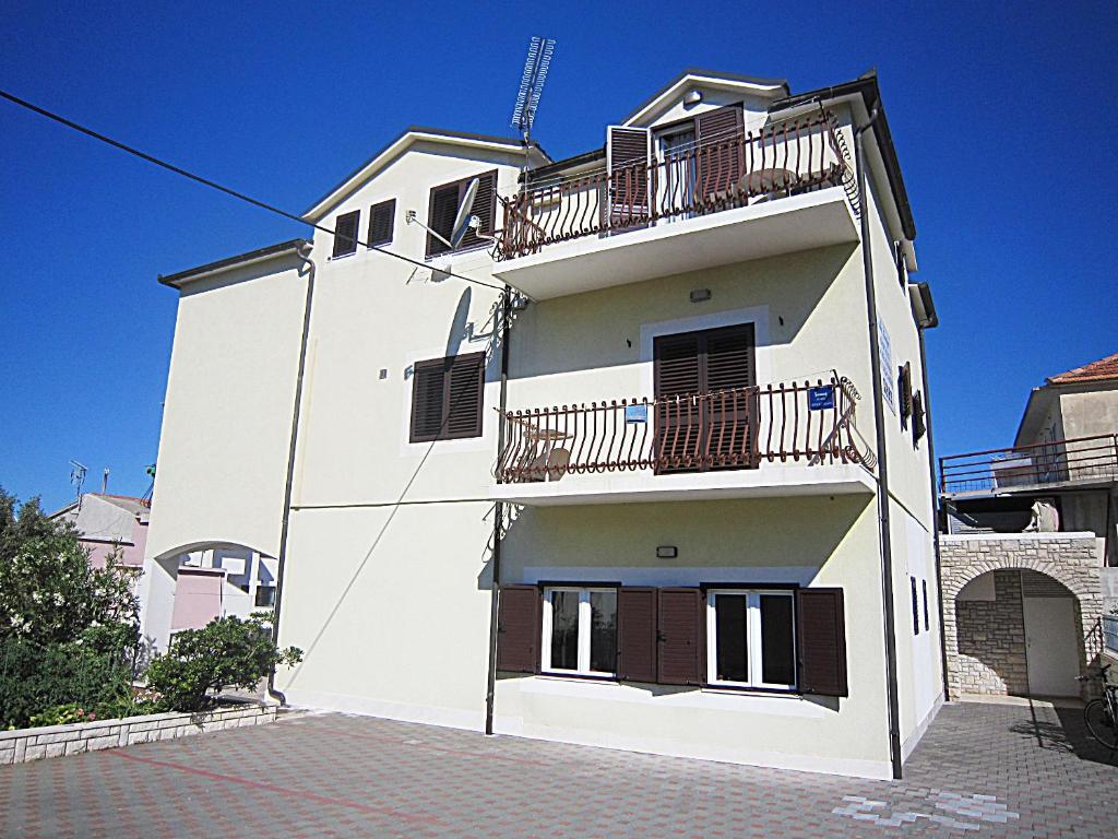 a white building with balconies on the side of it at Villa Lucia premium rooms in Primošten