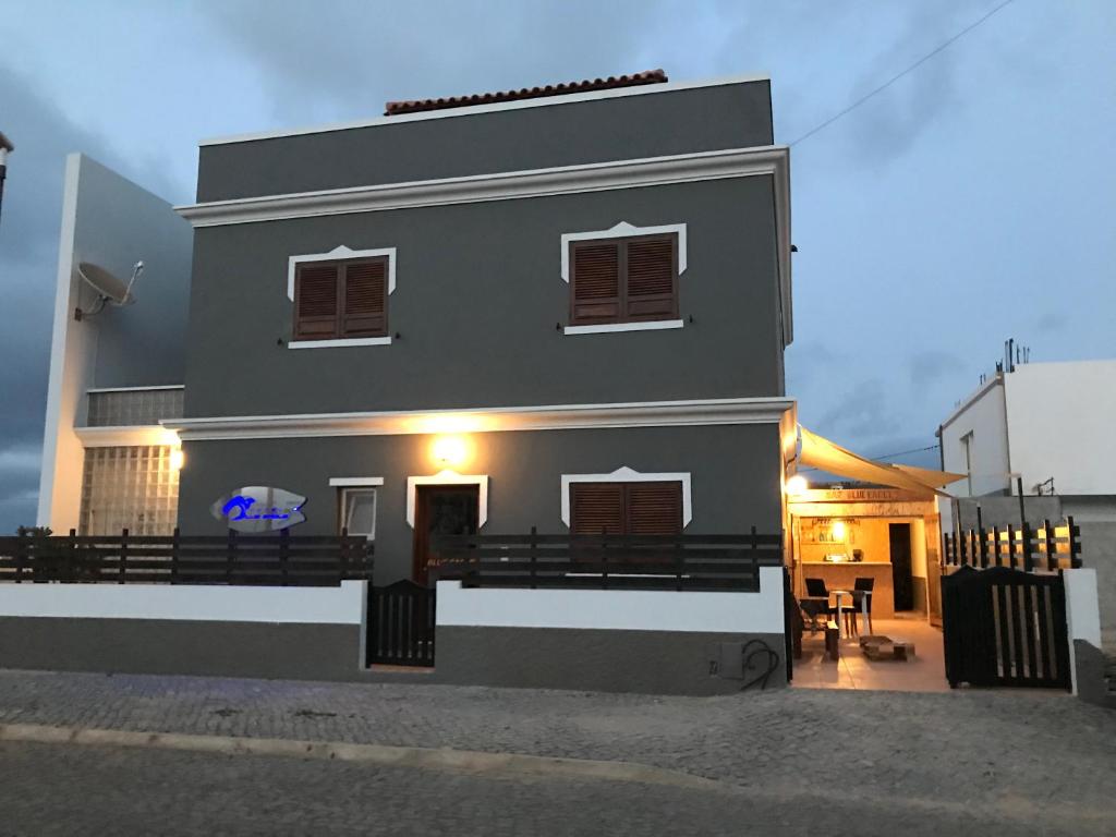 a white house with a porch with a table and chairs at Blue eagle Guesthouse in Santa Maria