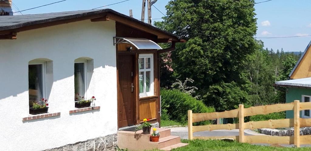 uma pequena casa com uma porta de madeira e uma cerca em Apartament 600 npm em Piechowice