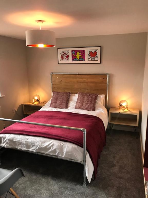 a bedroom with a large bed with a red blanket at 3 Crown Barton, Glastonbury in Glastonbury