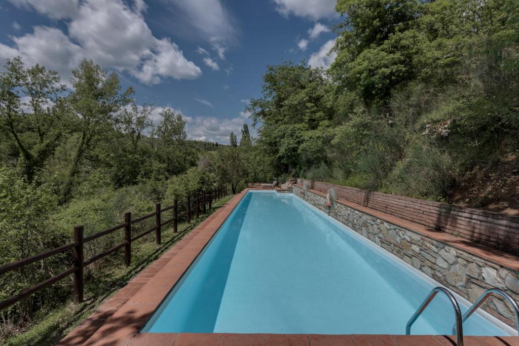 ein blauer Pool mit einem Zaun und Bäumen in der Unterkunft Ultimo Mulino Wellness Country Hotel in Gaiole in Chianti