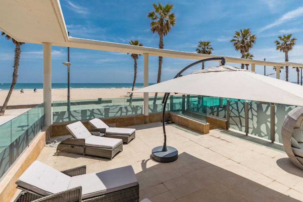 バレンシアにあるLuxury Beach Front Apartment with Poolのパティオ(椅子、パラソル付)、ビーチが備わります。