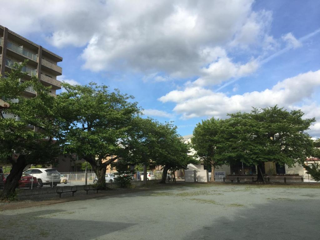 un aparcamiento con árboles frente a un edificio en Heart Hostel and Diner 女性専用Onlyfemale, en Ise