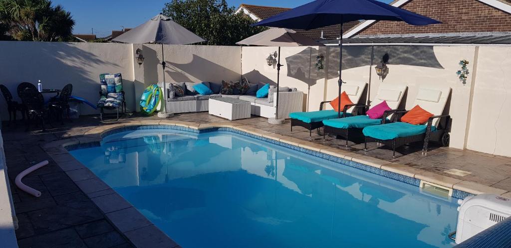 a swimming pool with some chairs and an umbrella at Harbour Lights, 30 Manor Lane in Selsey