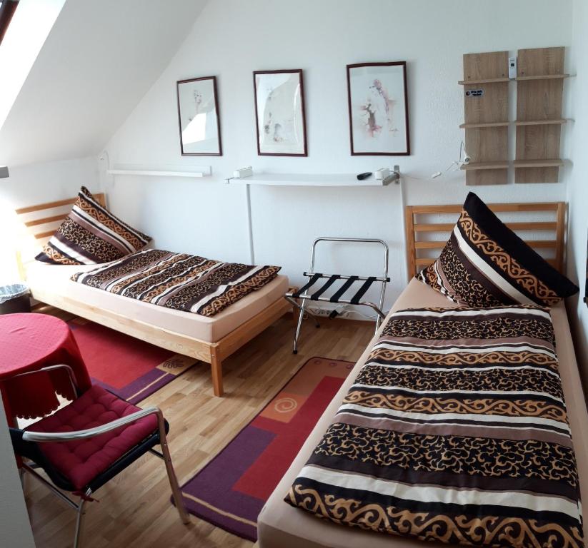 a room with two beds and a chair in it at Zwei ruhige, private Gästezimmer nahe U-Bahn in Nürnberg