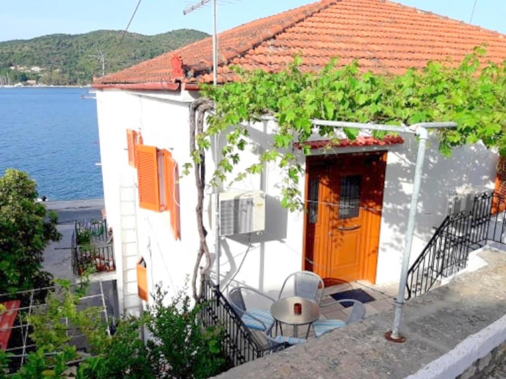 a white house with an orange door and some vines at ARITI HOLIDAY APARTMENT in Vathi