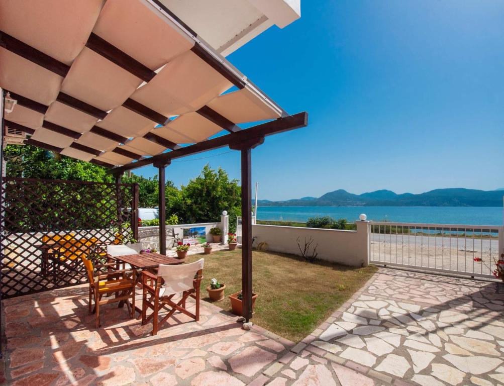 patio ze stołem i krzesłami pod pergolą w obiekcie Irini seaside studios w mieście Nikiana