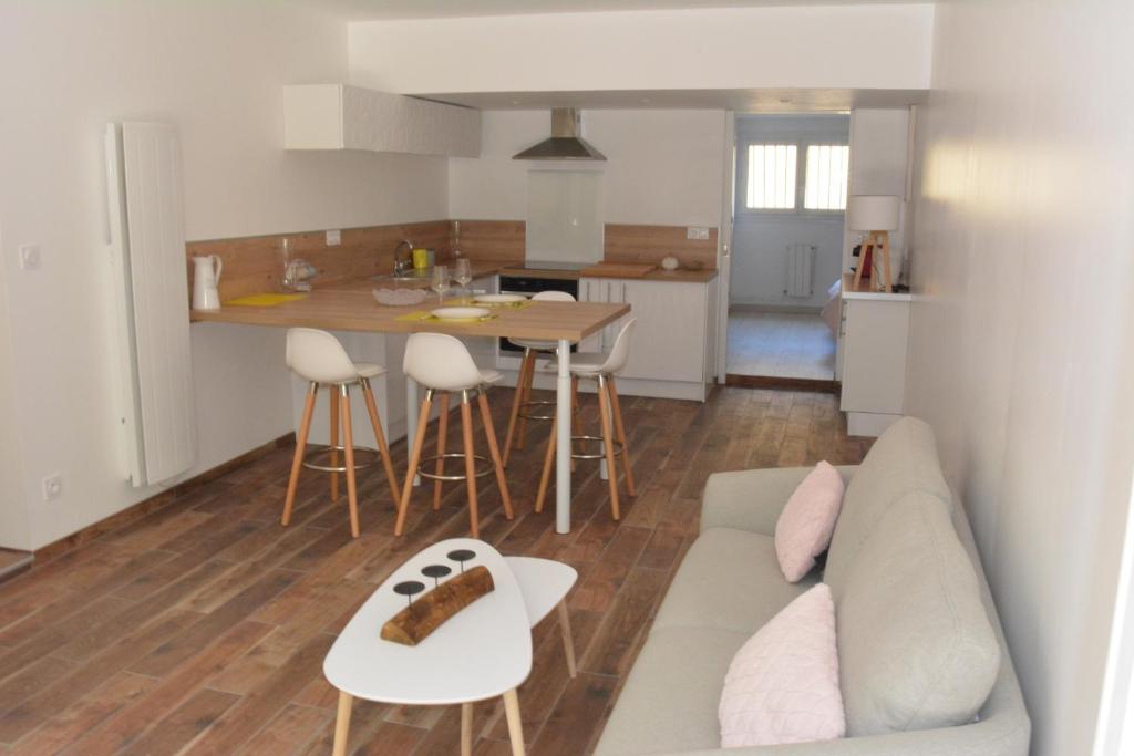 a living room and kitchen with a couch and a table at Villa Fleur des Pins 2 personnes Dune du Pyla in Gujan-Mestras