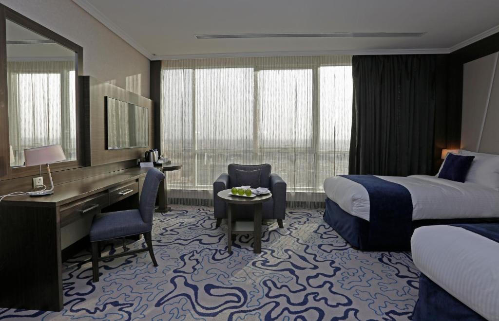 a hotel room with a bed and a desk and a desk at Swiss Flora Royal Hotel Riyadh in Riyadh