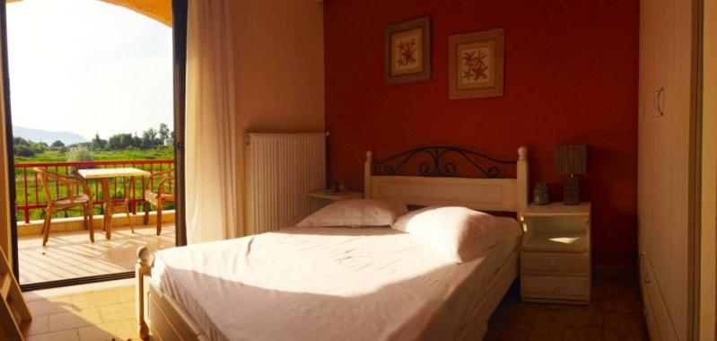sypialnia z łóżkiem i balkonem w obiekcie Aenaon Studios w mieście Oreoi