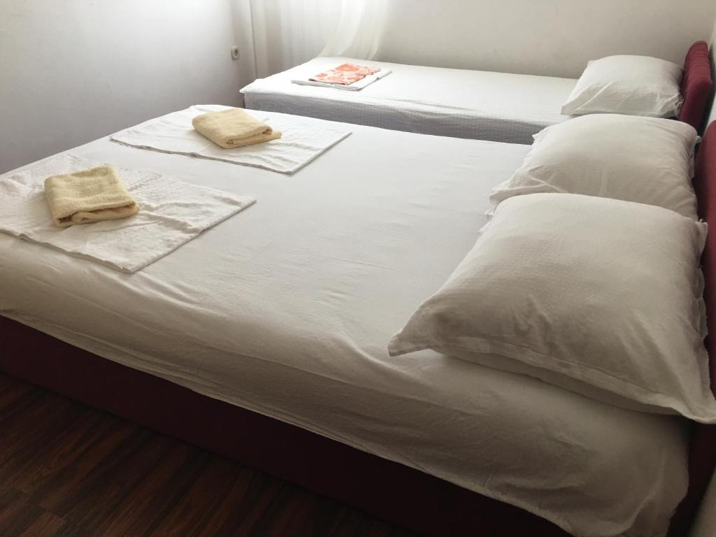 2 Betten mit weißer Bettwäsche und Handtüchern darauf in der Unterkunft Apartmani Glavina in Zaostrog