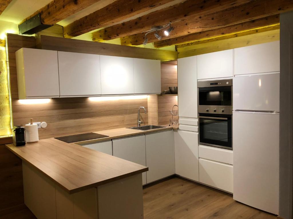 a kitchen with white cabinets and a wooden ceiling at Apartament Piteus Centre in Sant Llorenç de Morunys