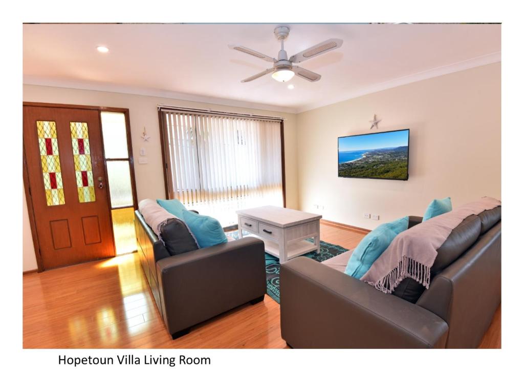 uma sala de estar com 2 sofás e uma ventoinha de tecto em Hopetoun Villa em Woonona