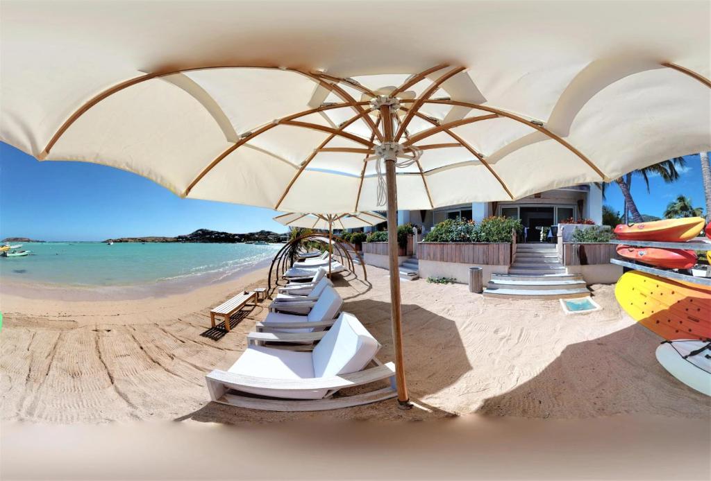 una playa con una fila de sillas y una sombrilla en Hotel Les Ondines Sur La Plage, en Gustavia