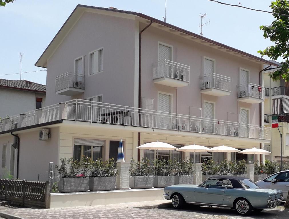 a blue car parked in front of a building with umbrellas at B&b villa lambusta in Cesenatico