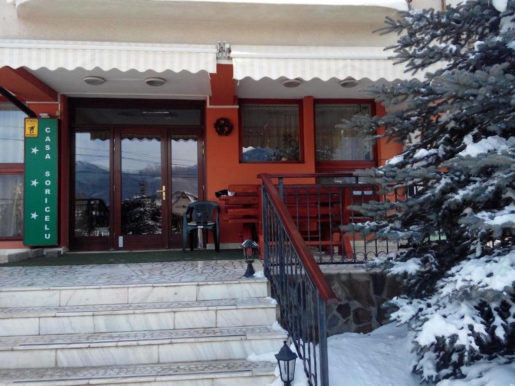 una casa arancione con neve sul portico e le scale di CASA SORICELU a Săcele