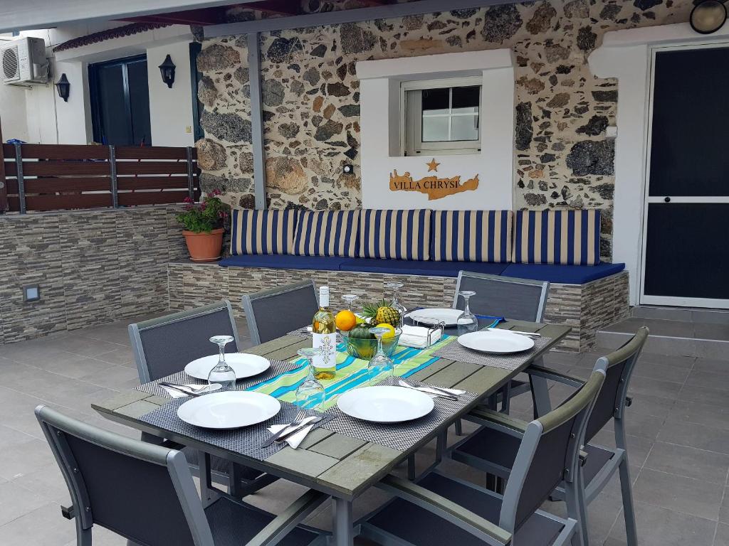 einem Holztisch mit Stühlen und Tellern darauf in der Unterkunft VILLA CHRYSI in Agalianós