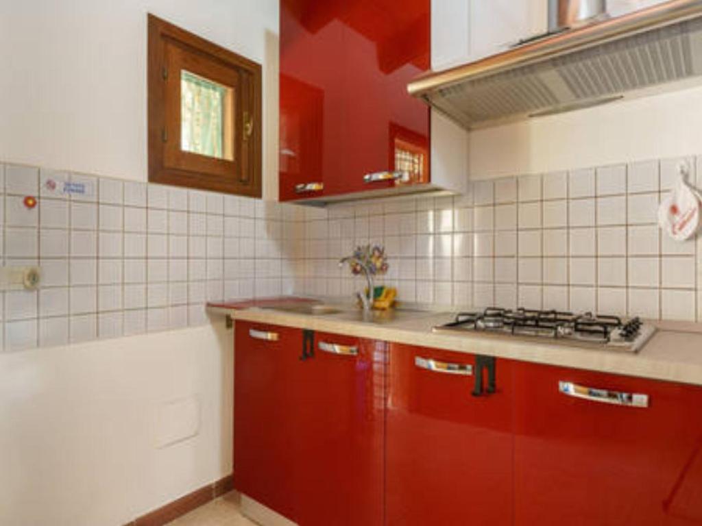 - une cuisine avec des placards rouges et une cuisinière dans l'établissement Casa Aloha San Vito Lo Capo, à San Vito Lo Capo