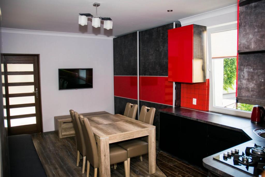 a kitchen with a wooden table and red cabinets at Apartament 250m od morza! in Ustka