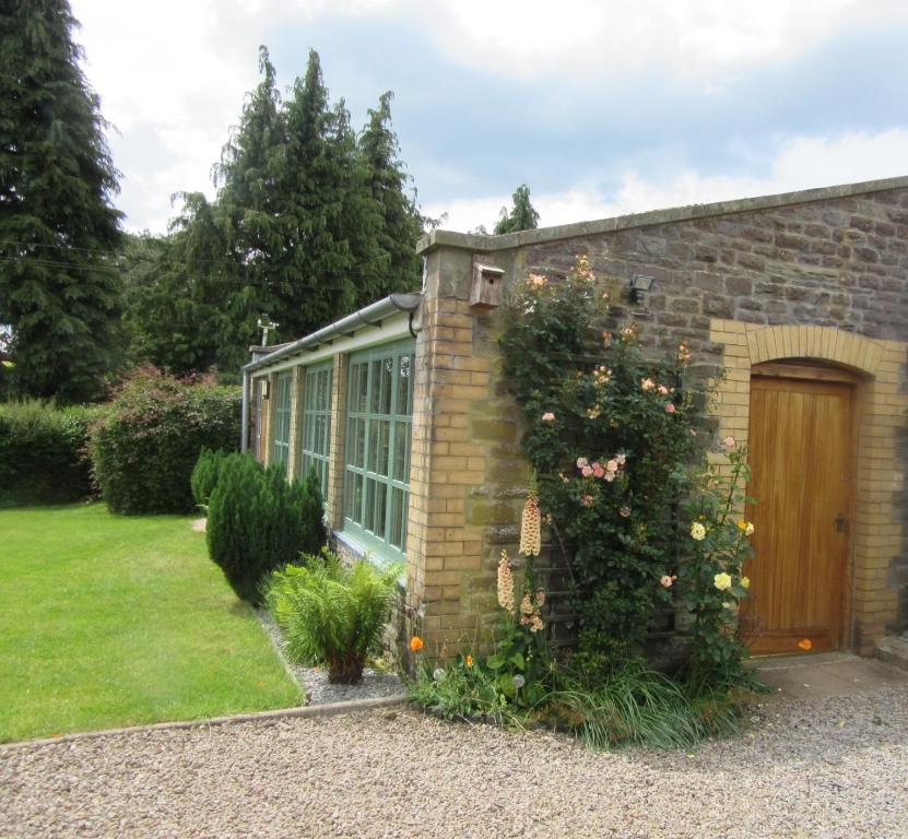 uma casa de tijolos com uma porta de madeira e um quintal em Tegfan Garden Suite em Talgarth