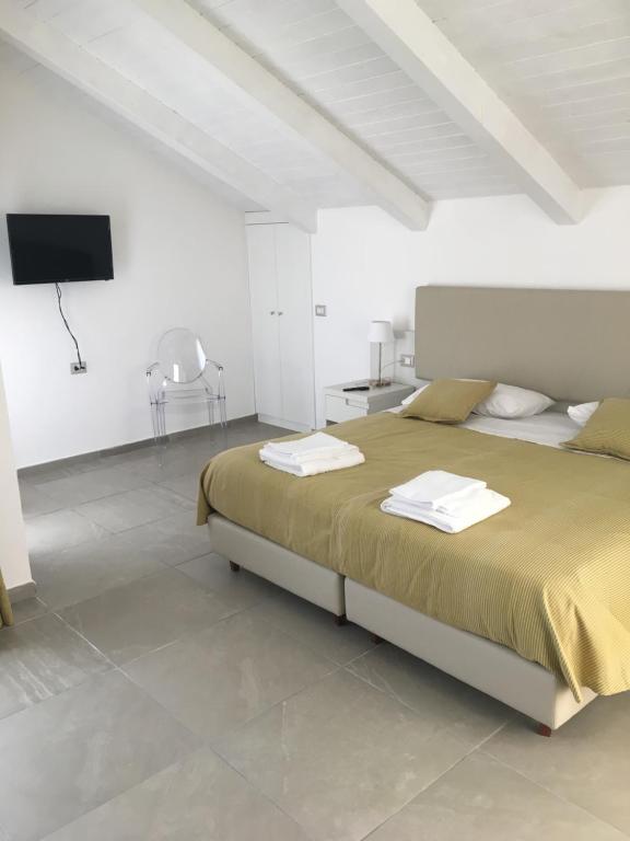 a white bedroom with a bed and a flat screen tv at Villa Donatella in Paestum