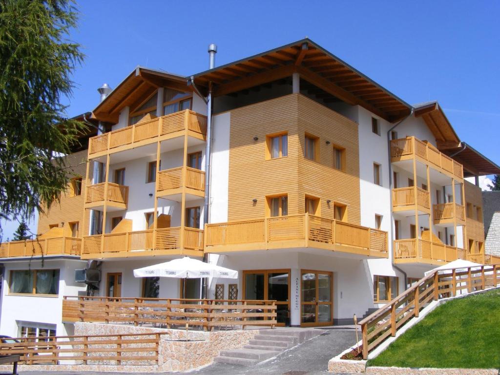 a large building with wooden balconies and tables at Alpine Mugon Hotel in Vason