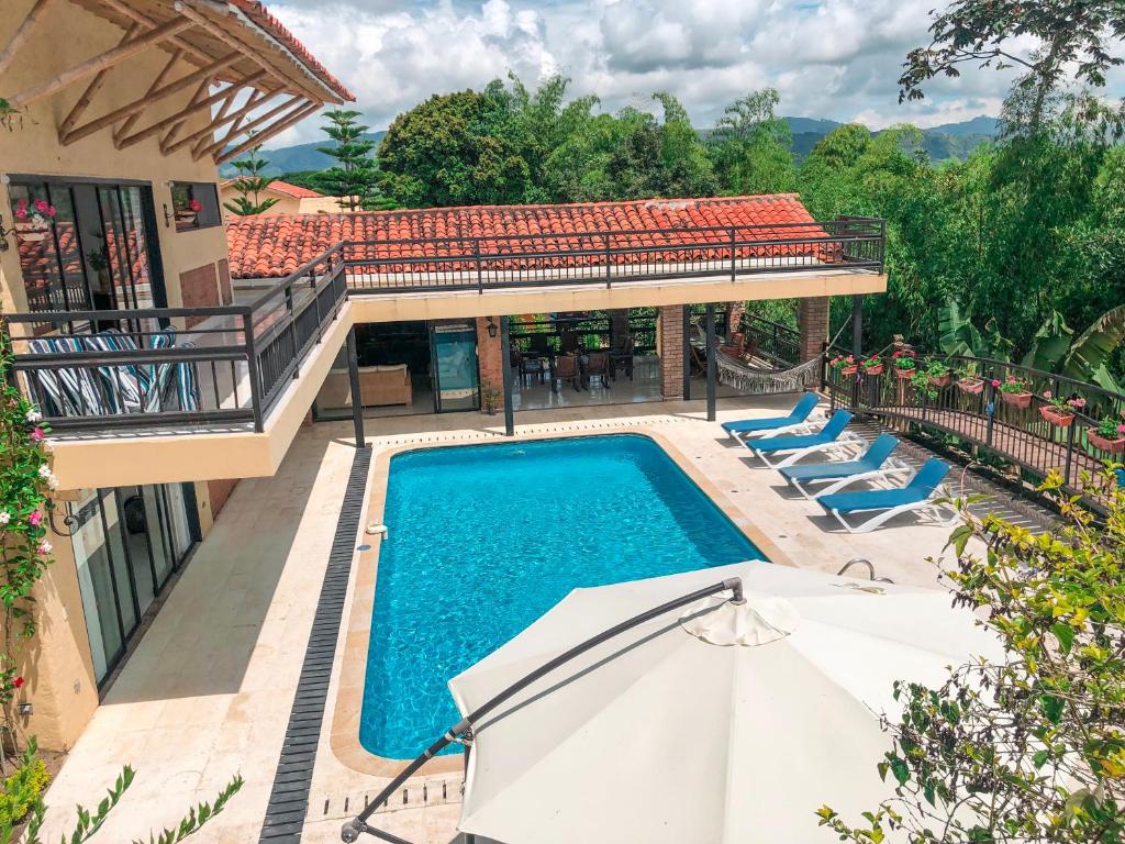 an outdoor swimming pool with chairs and an umbrella at Finca Panaca Herrería 8 in Quimbaya