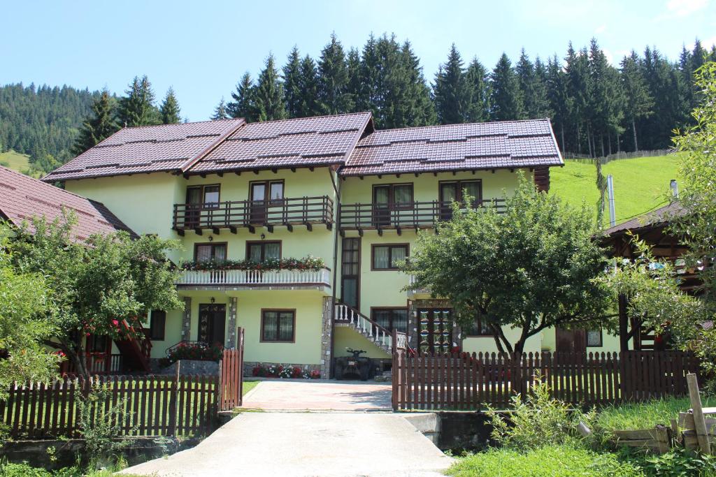 a large yellow house with a wooden fence at Piscul Muntelui in Moieciu de Sus