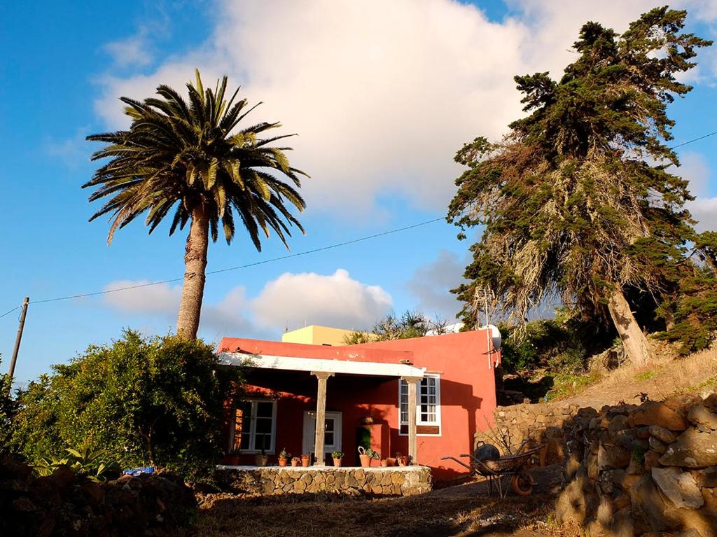 uma casa vermelha com uma palmeira em frente em EL LAGAR DEL NORTE em Erese