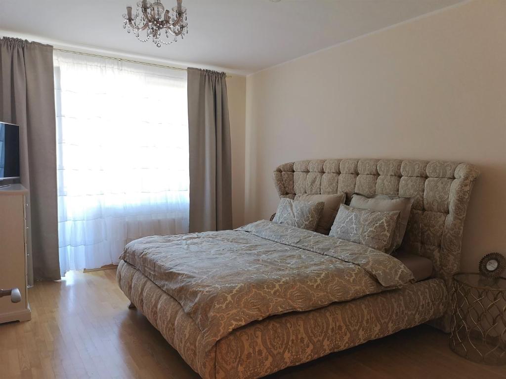 um quarto com uma cama grande e um lustre em Julia apartments next to AQUA PARK em Druskininkai