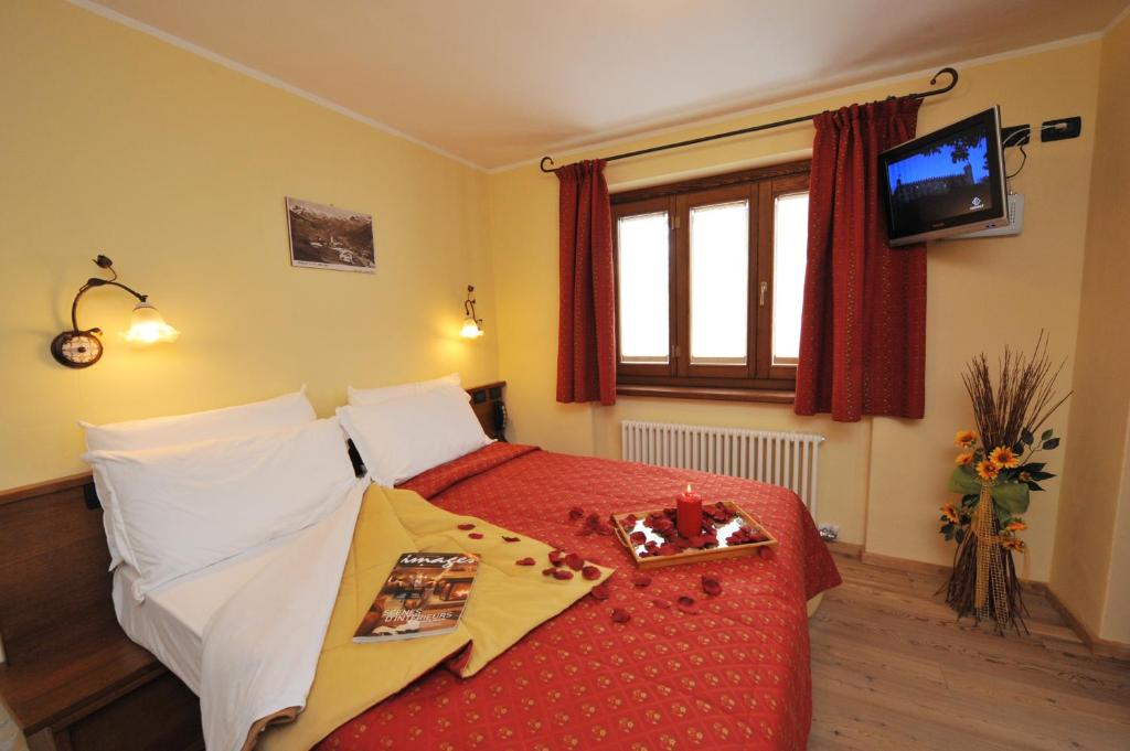 a bedroom with a bed with a red bedspread at Hotel Le Petit Abri in Champoluc