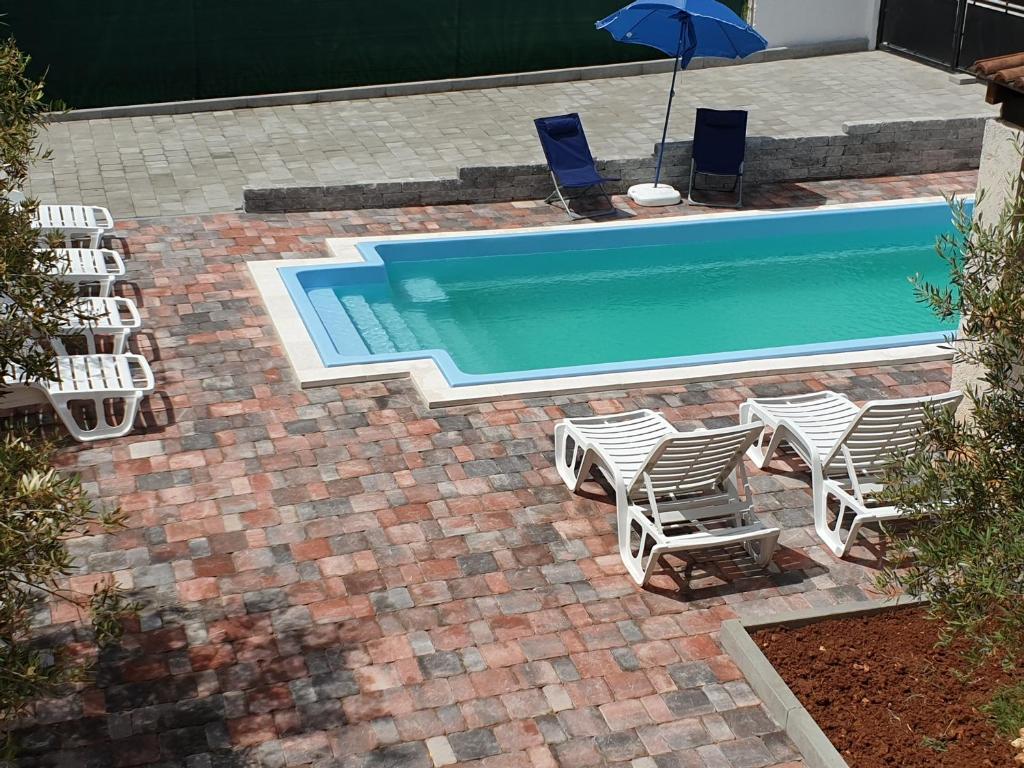 a group of chairs and a swimming pool with an umbrella at Villa Arancia in Peruški