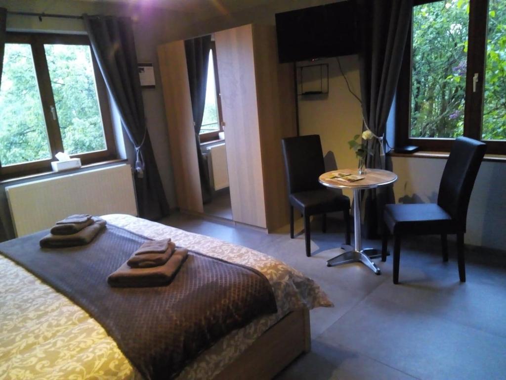 een slaapkamer met een bed en een tafel en stoelen bij Votre Horizon in Aywaille