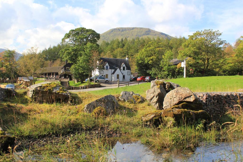 uma casa num campo com pedras na relva em Clachaig Inn em Ballachulish