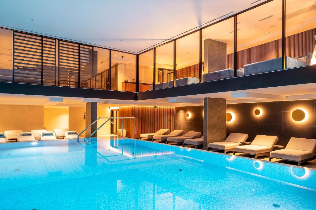 a large swimming pool in a hotel with chairs at Luxury Hotel Riva in Malinska