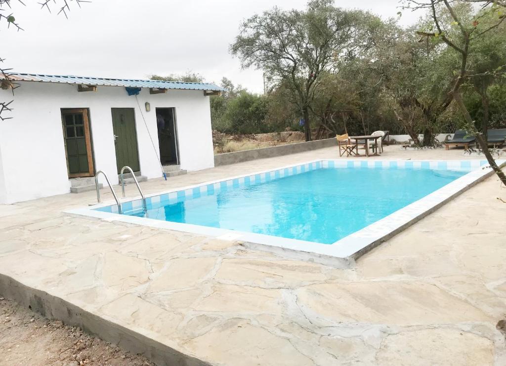 a swimming pool in front of a house at Maasai Simba Camp in Amboseli