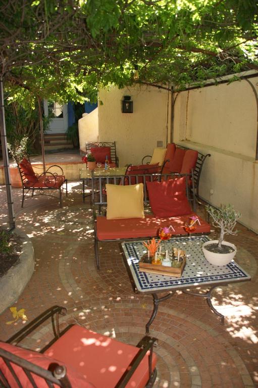 a patio with chairs and tables under a tree at Auberge des Glycines in Porquerolles