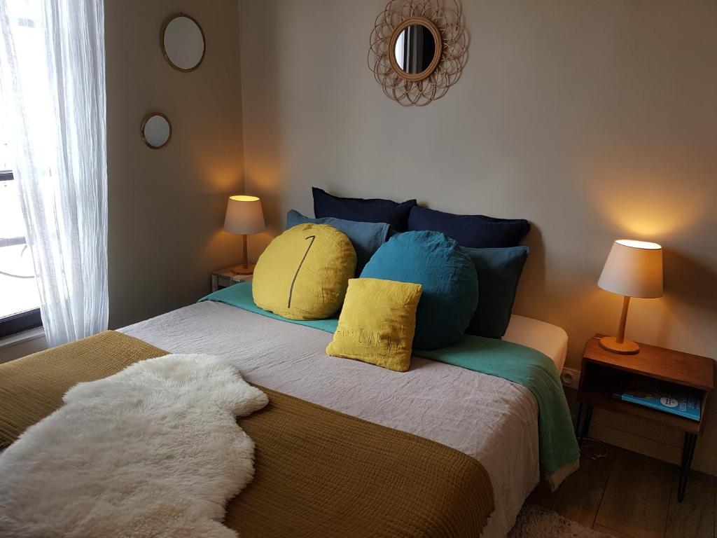1 dormitorio con 1 cama con almohadas azules y amarillas en L'Echiquier de Normandie confort cosy et vue premium, en Rouen