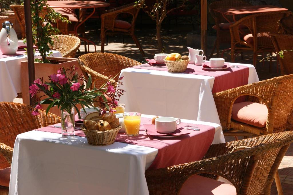 two tables with white table cloths and flowers on them at Auberge des Glycines in Porquerolles