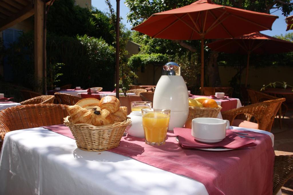 a table with baskets of bread and a bottle of milk at Auberge des Glycines in Porquerolles