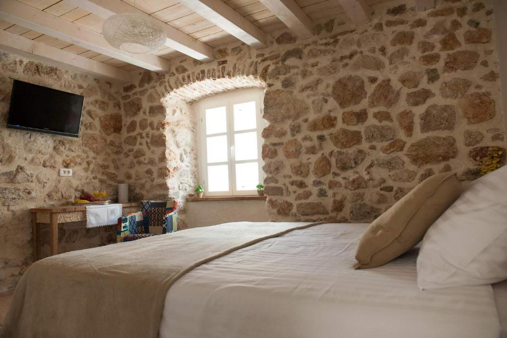 a bedroom with a large bed with a stone wall at Sobe Bile in Pag