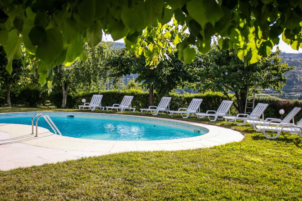 um grupo de espreguiçadeiras em redor de uma piscina em Quinta Das Rossadas em Cinfães