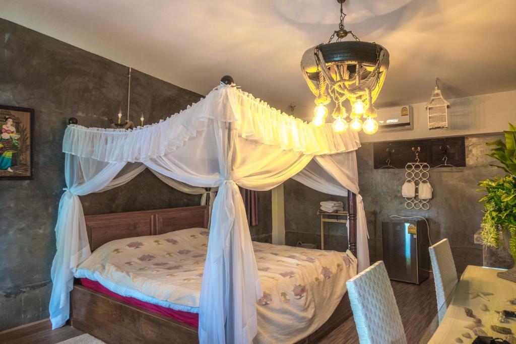 1 dormitorio con cama con dosel y lámpara de araña en The Quarter Wutthakat en Bang Khun Thian