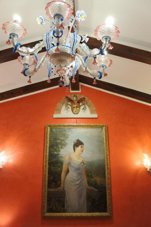 Un dipinto di una donna su un muro con un lampadario. di Casa Torretta a Venezia